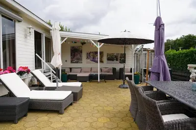 a patio with a table and chairs and an umbrella at Chalet with waterfront sauna and boat in Loosdrecht