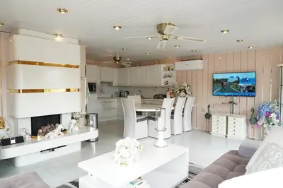 a kitchen and living room with white furniture and a tv at Chalet with waterfront sauna and boat in Loosdrecht