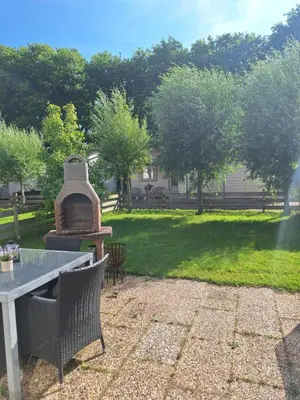 a patio with a grill in a yard with a table at Rekerlanden 133 in Warmenhuizen