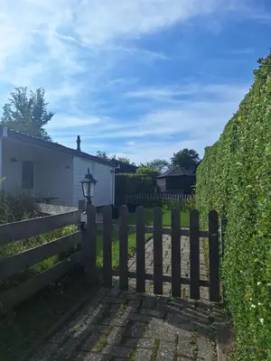 a wooden fence in front of a hedge at Rekerlanden 133 in Warmenhuizen