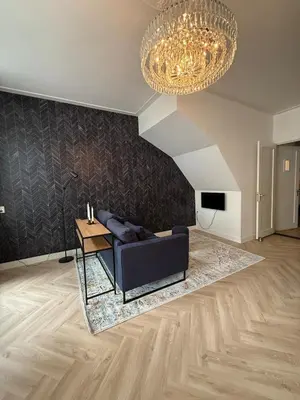 a living room with a blue couch and a chandelier at The Blue House in Alkmaar