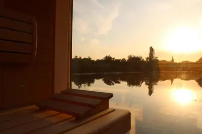 a room with a view of a lake with the sunset at Temple of Hedon Wellness Spa and Sleep in Ankeveen