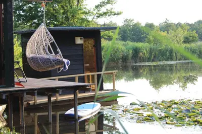 a hammock on a dock next to a lake at Temple of Hedon Wellness Spa and Sleep in Ankeveen