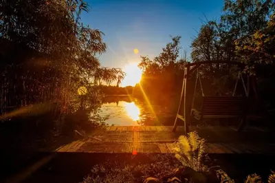 a sunset over a body of water with a bench at Temple of Hedon Wellness Spa and Sleep in Ankeveen
