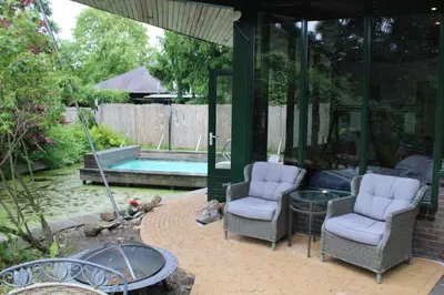a patio with two chairs and a swimming pool at Temple of Hedon Wellness Spa and Sleep in Ankeveen