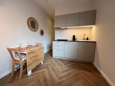 a small kitchen with a wooden table and a counter at The Dune house, Free parking in Zandvoort