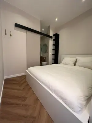 a bedroom with a large white bed and wooden floors at The Dune house, Free parking in Zandvoort