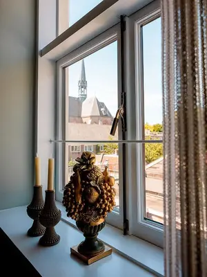 a window with a vase on a table with two candles at Suites aan de Gracht Utrecht in Utrecht
