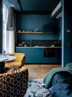 a kitchen with blue walls and a table and a chair at Suites aan de Gracht Utrecht in Utrecht