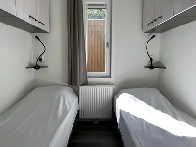 two beds in a small room with a window at Samoza in Ons Belang