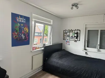 a bedroom with a black bed and two windows at Paleisje aan zee in IJmuiden