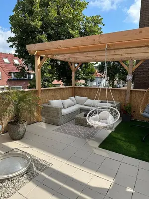 a patio with a swing and a hammock at Paleisje aan zee in IJmuiden