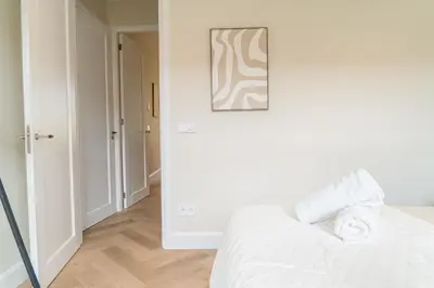 a white bedroom with a bed and a picture on the wall at Charming Jordaan Apartment, Canal Views in Amsterdam