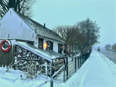a house in the snow next to a fence at Guesthouse Het Woerdense Veerhuis in Woerden