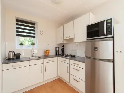 a kitchen with white cabinets and a stainless steel refrigerator at Holiday Home near Dutch Coast & Forest in Noordwijk