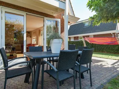 a table with chairs and a potted plant on a patio at Holiday Home near Dutch Coast & Forest in Noordwijk