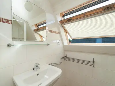 a white bathroom with a sink and a mirror at Holiday Home near Dutch Coast & Forest in Noordwijk