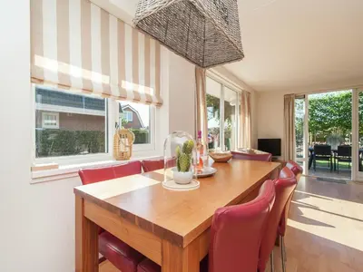a dining room with a wooden table and red chairs at Holiday Home near Dutch Coast & Forest in Noordwijk