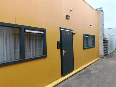 a yellow building with a black door and windows at Stijlvolle Designstudio in Almere