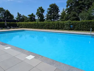 a large blue swimming pool in a yard at Holiday House 4 guests at Spaarnwoude in Velsen-Zuid