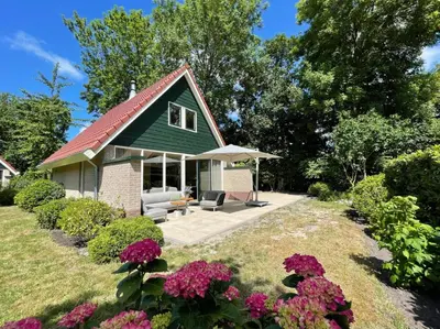 a small house with a green roof and flowers at Zon in de Duinen by Droomvilla in Sint Maarten