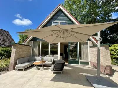 a large tan umbrella on a patio at Zon in de Duinen by Droomvilla in Sint Maarten
