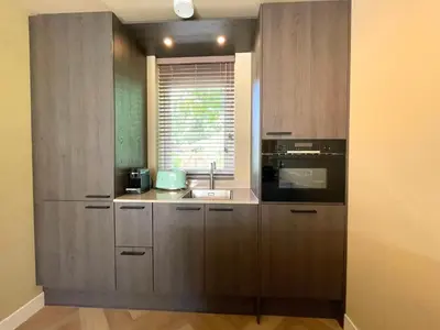 a kitchen with wooden cabinets and a sink and a window at Zon in de Duinen by Droomvilla in Sint Maarten