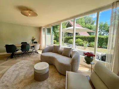 a living room with a couch and a large window at Zon in de Duinen by Droomvilla in Sint Maarten