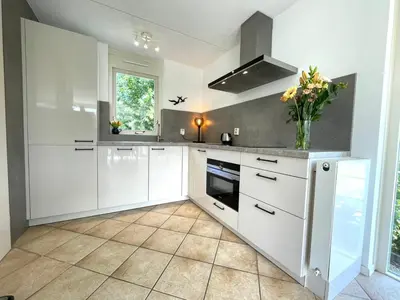 a kitchen with white cabinets and a vase of flowers at Zon op de Wielen by Droomvilla in Sint Maarten