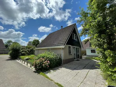 a small house with a black roof and a driveway at Zon op de Wielen by Droomvilla in Sint Maarten