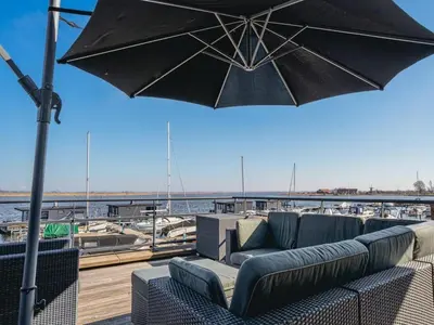 a patio with a couch and an umbrella at Nova Meer in Uitgeest
