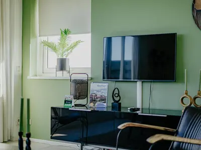 a living room with a table and a tv on a wall at Nova Meer in Uitgeest