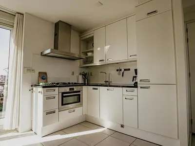 a white kitchen with white cabinets and a window at Nova Meer in Uitgeest