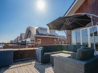 a patio with a couch and an umbrella at Nova Meer in Uitgeest