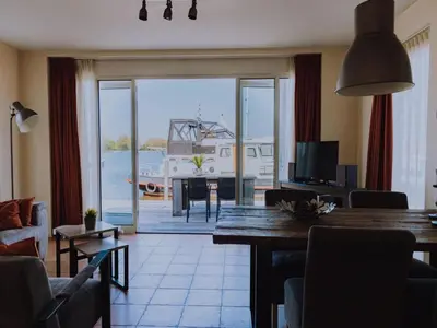 a living room with a table and a view of a boat at Waterbase in Uitgeest
