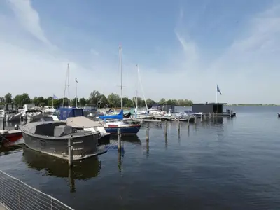 a group of boats docked at a dock in the water at Waterbase in Uitgeest