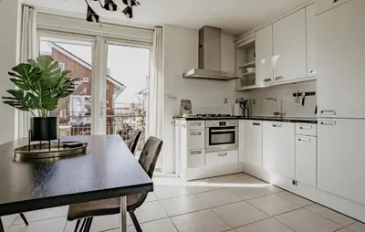 a kitchen with white cabinets and a table with a potted plant at Oostergeest Beneden 2 Slaapk in Uitgeest
