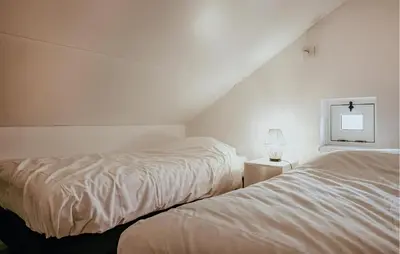 a bedroom with two beds and a cross on the wall at Oostergeest Beneden 2 Slaapk in Uitgeest