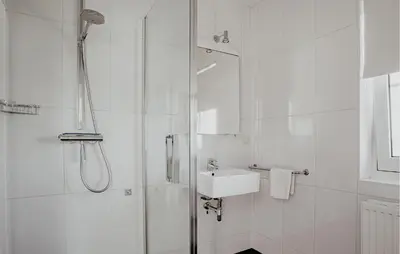 a white bathroom with a shower and a sink at Oostergeest Beneden 2 Slaapk in Uitgeest