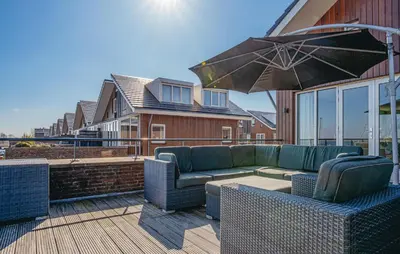 a patio with a couch and an umbrella at Oostergeest Beneden 2 Slaapk in Uitgeest