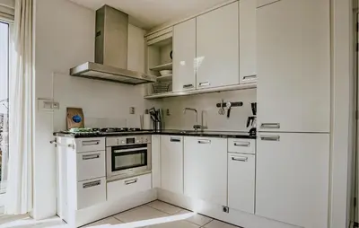 a white kitchen with white cabinets and a sink at Oostergeest Beneden 2 Slaapk in Uitgeest