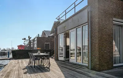 a patio with a table and chairs on a wooden deck at Westergeest Beneden 2 Slaapk in Uitgeest