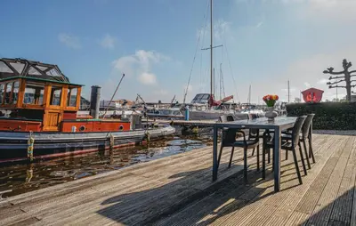 a table and chairs sitting on a dock with boats at Westergeest Beneden 2 Slaapk in Uitgeest