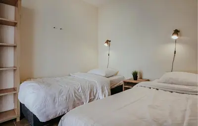 two beds in a room with white sheets at Westergeest Beneden 2 Slaapk in Uitgeest