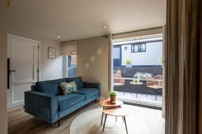 a living room with a blue couch and a table at Beachbreak Boulevard in Katwijk aan Zee
