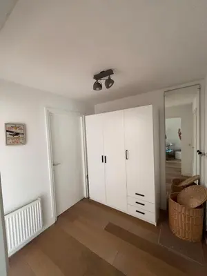 an empty living room with white cabinets and wood floors at Casa Luz & Luna in Akersloot