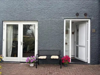 a bench sitting in front of a building with flowers at Casa Luz & Luna in Akersloot