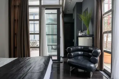 a black leather chair in a room with a bed at Zocher6 a monumental town house in the city center in Utrecht