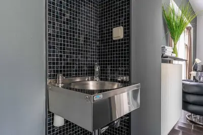 a bathroom with a sink and a black tiled wall at Zocher6 a monumental town house in the city center in Utrecht