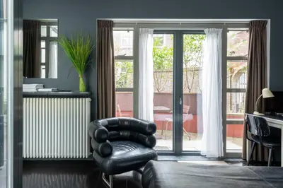 a black leather chair in a living room with sliding glass doors at Zocher6 a monumental town house in the city center in Utrecht
